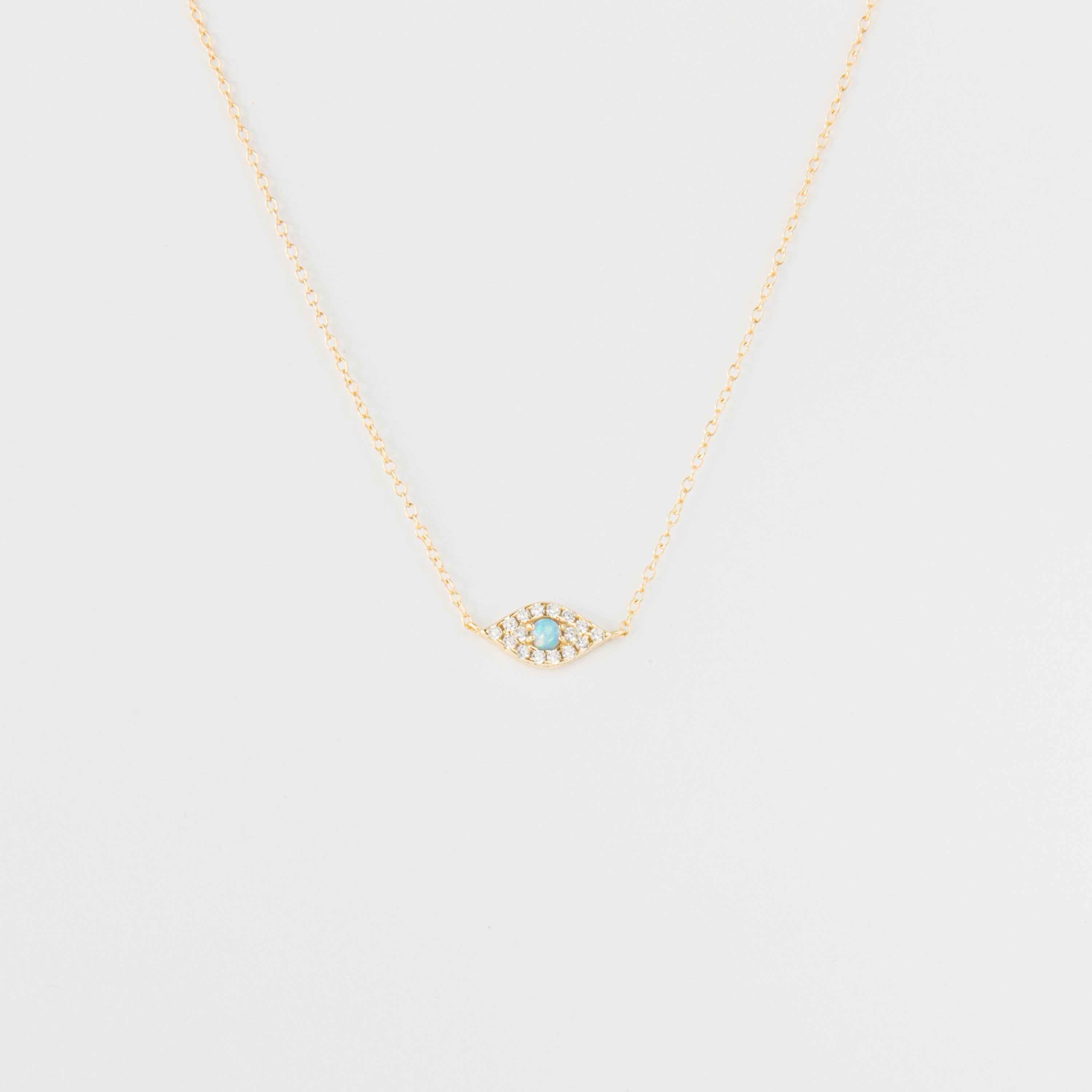 Opal Eye Necklace: Gold chain necklace with a small 925 sterling silver eye pendant set with turquoise and clear stones, shown on a white background.