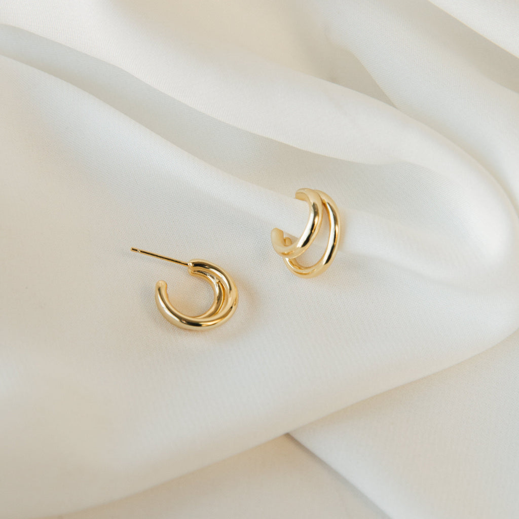 Zoey Duo Hoops rest on soft, white fabric with gentle folds—ideal for stacking or pairing with our Double Huggie Hoops for a chic, layered ear look.