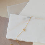 Elegant gold Pave Initial Bracelet featuring a delicate charm, showcased on a white marble slab.