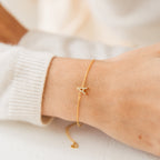 The Pave Initial Bracelet featuring an "A" charm is worn on the wrist over a cream-colored sweater sleeve.