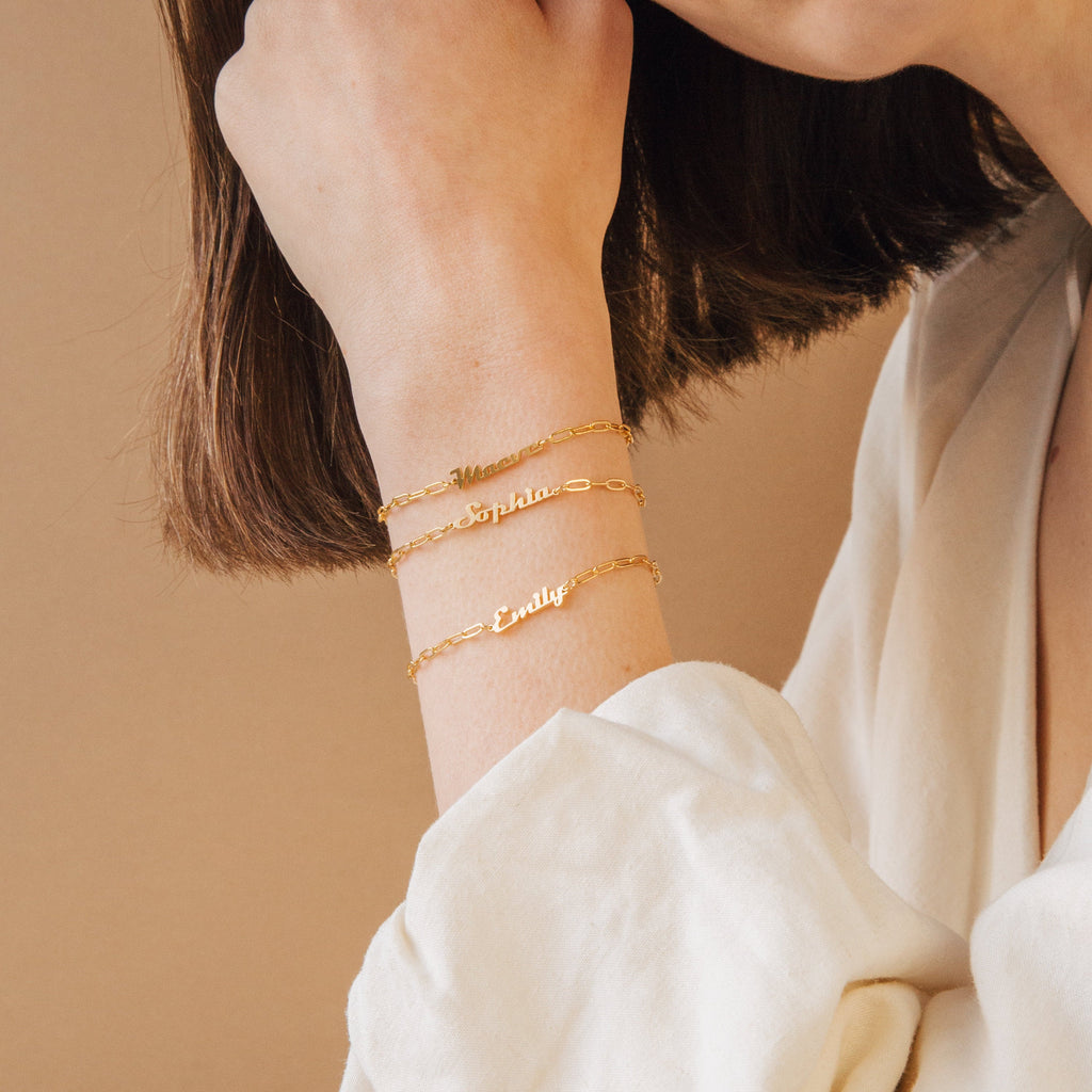 A woman wears two Name Link Bracelets, each personalized with "Sophia" and "Emily," highlighting the elegance and contemporary style of these custom jewelry pieces.
