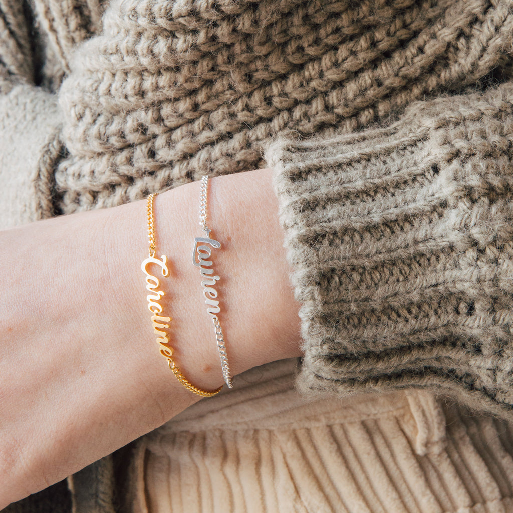 Wearing gold and silver Ladybirds Name Curb Bracelets personalized with "Caroline" and "Lauren" alongside a chunky knit sweater creates a modern, stylish look.