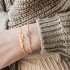 Wearing gold and silver Ladybirds Name Curb Bracelets personalized with "Caroline" and "Lauren" alongside a chunky knit sweater creates a modern, stylish look.