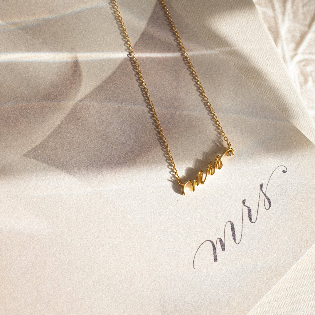 The Mrs. Necklace, an ideal wedding gift, is displayed on paper adorned with mrs in elegant script.
