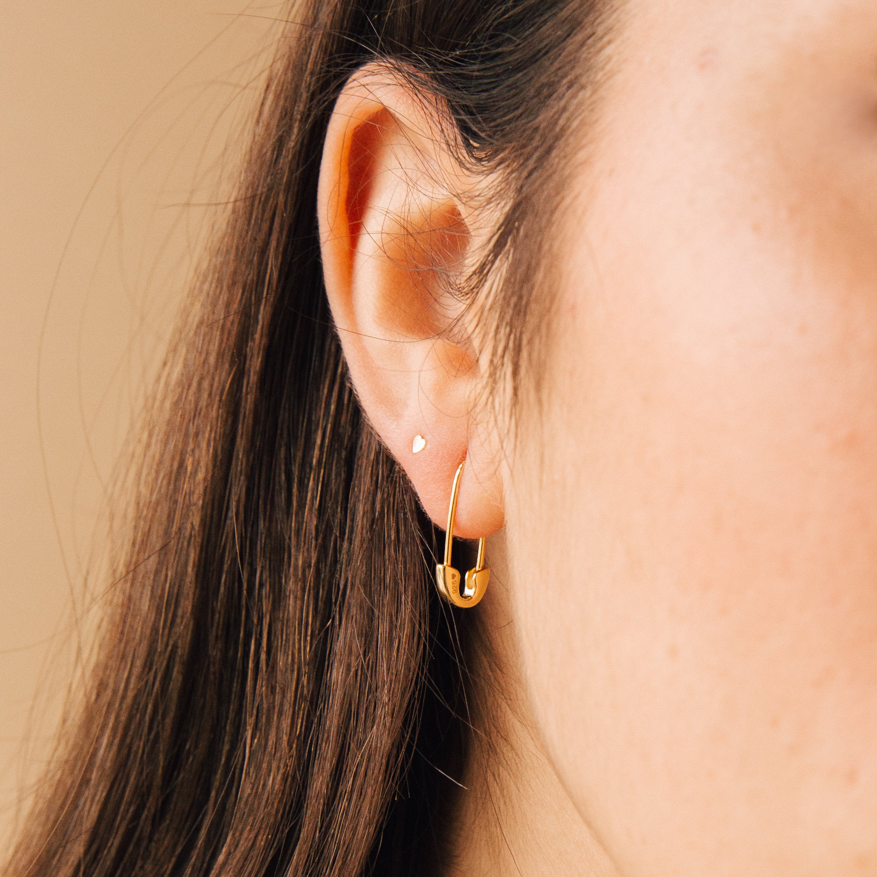 Close-up of a woman's ear with a small stud and the Ava Earrings—a unique twist on funky gold earrings for a bold yet chic statement.
