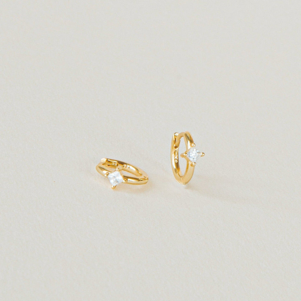A pair of Athena Huggies crafted in gold and delicately accented with a sparkling diamond.