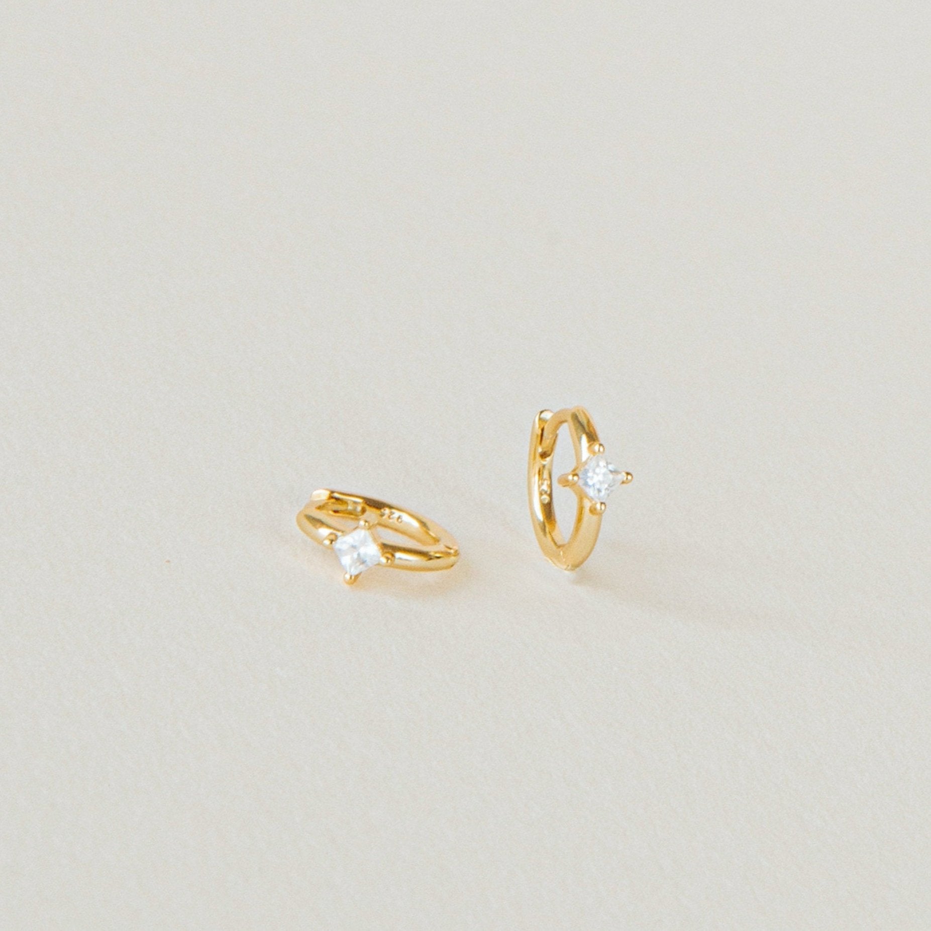 A pair of Athena Huggies crafted in gold and delicately accented with a sparkling diamond.