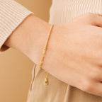 The Klara Tennis Bracelet shines on a wrist alongside a beige long-sleeve top—ideal for those who appreciate minimalist jewelry.