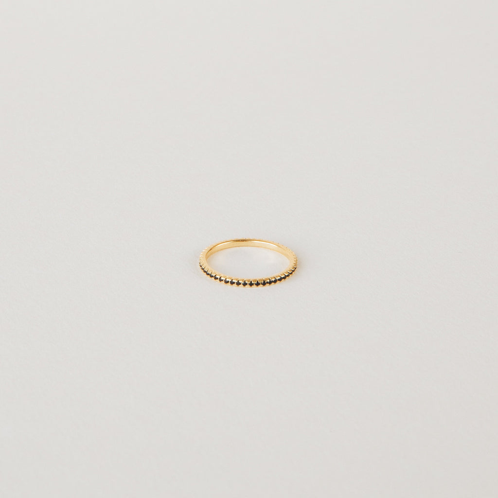 The Amber Eternity Ring is a delicate gold, stackable ring featuring small beads along its band, shown on a plain white background.