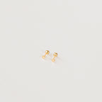 The Tiny Heart Studs in 18K Gold are a perfect gift, featuring delicate heart-shaped gold studs on a white surface—ideal for everyday wear.