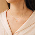 Rae Diamond Necklace with small round diamond pendant on delicate 18K gold chain worn on model's neck.