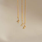 Three delicate necklaces with sparkling pave initial K pendants hang against a light, neutral background—a stylish Dangling Pave Initial Necklace, perfect as a thoughtful gift for women.