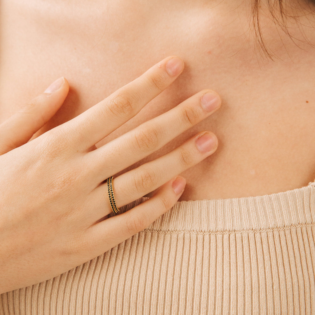 A hand wearing the Amber Eternity Ring rests on a chest above a beige ribbed top.