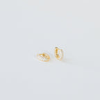 Kira Pave Huggies in small gold feature pavé white stones and are displayed on a plain white surface.