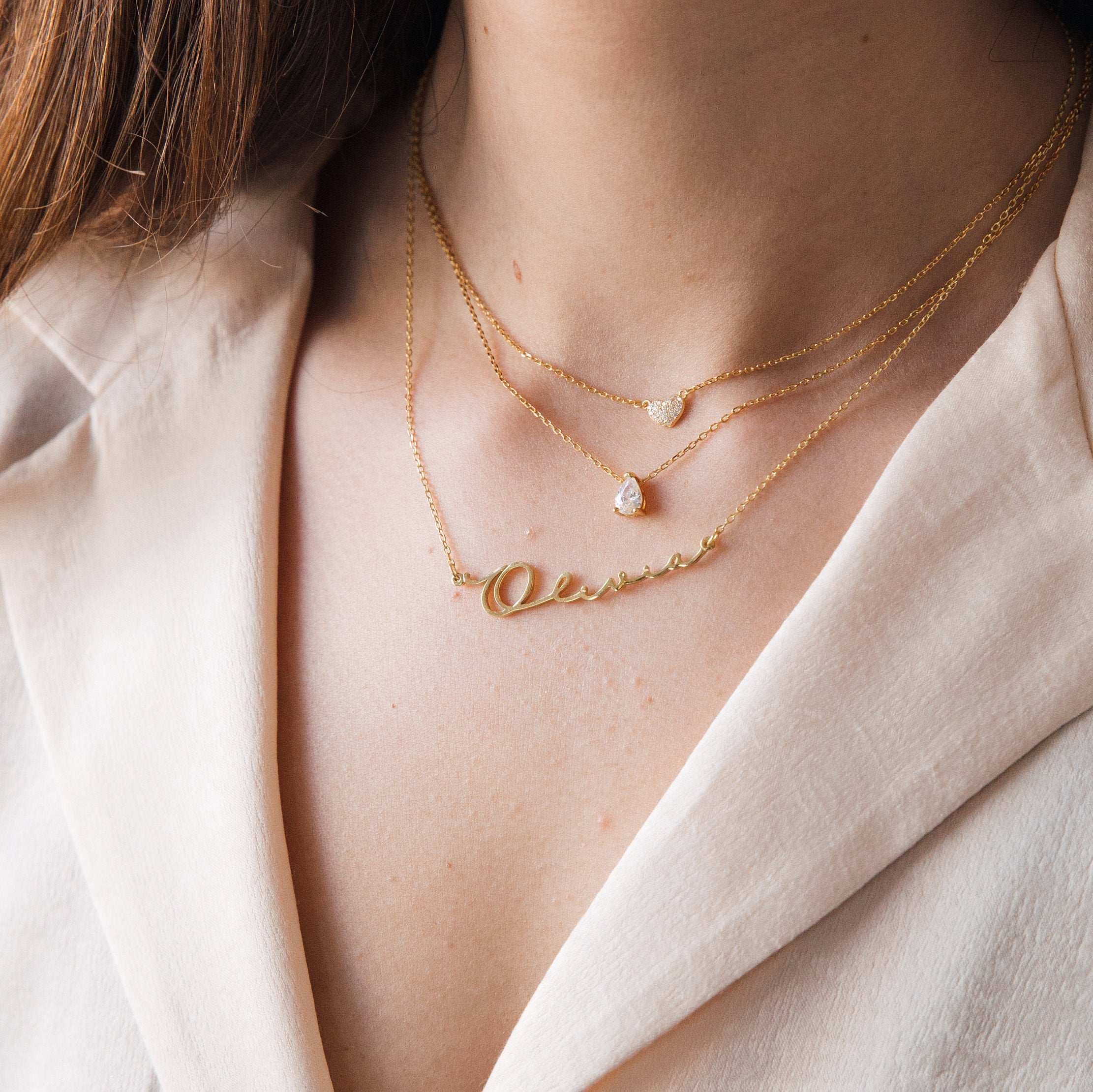 Rae Diamond Necklace layered with a small diamond and gold chain on a woman in a cream blouse.