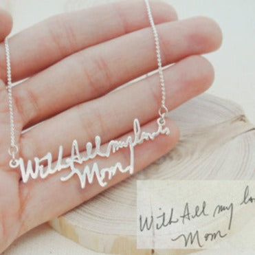 The Handwriting Necklace features a silver pendant engraved in cursive with "With All my love, Mom," making it a sentimental gift for meaningful moments.